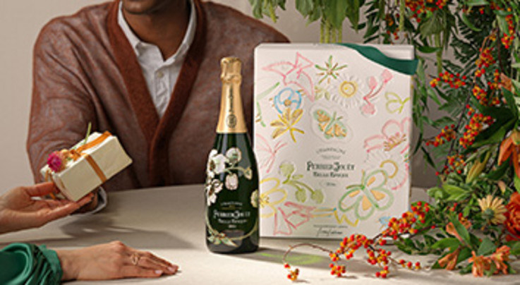 Eine festliche Szene mit einer Champagnerflasche, einer stilvollen Geschenkbox und einer Hand, die ein kleines Geschenk überreicht. Im Hintergrund sind dekorative Pflanzen zu sehen.